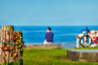 Scenic view of sea against clear blue sky with sitting person