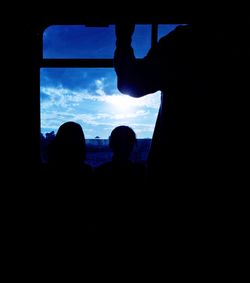 Silhouette people against sky seen through window