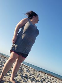 Midsection of man on beach against clear sky