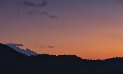 Scenic view of silhouette mountains against orange sky