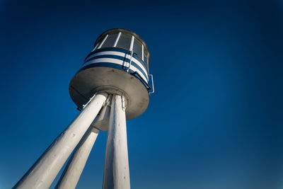 Low angle view of communications tower against clear blue sky