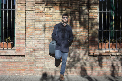 Portrait of man in sunglasses leaning on brick wall