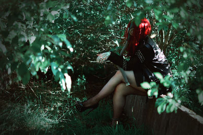 Side view of woman wearing gas mask sitting amidst plants