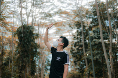 Full length of young woman standing against trees