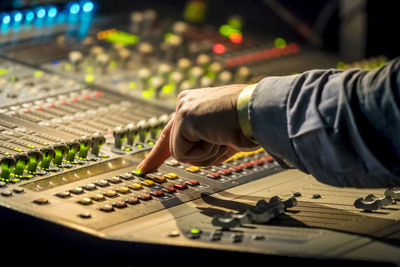 Cropped hand of male dj pressing push button on control panel during music concert