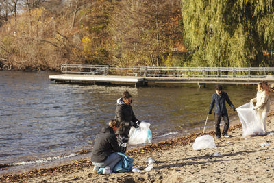 Male and female friends collecting plastic garbage by lake