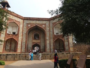 People in historic building against clear sky