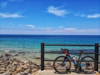 Bicycle by sea against blue sky