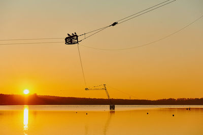 Silhouette power lines against sky during sunset