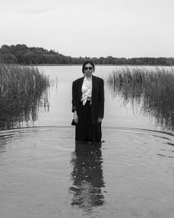 Man standing by lake against sky