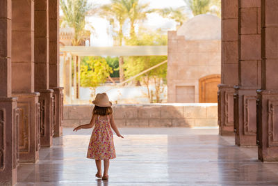 Pretty little girl walks slowly down the portico among the columns