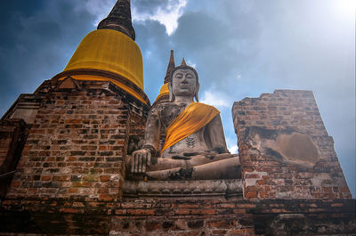 Low angle view of buddha statue against cloudy sky