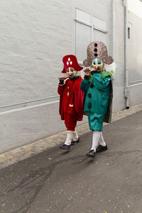 Full length rear view of boy standing on red umbrella