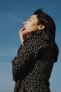 Side view of a young woman looking away against sky
