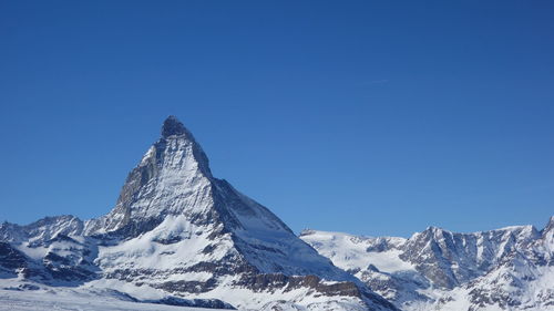 Scenic view of snowcapped mountains against clear blue sky