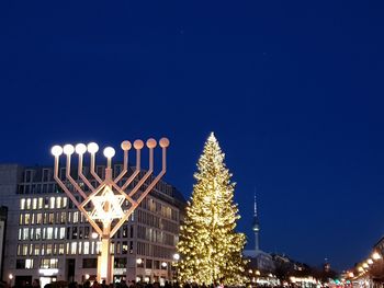 Low angle view of illuminated christmas tree against sky at night