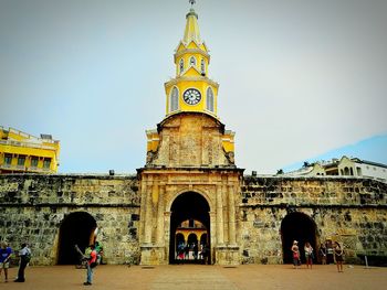 People in front of historical building against sky