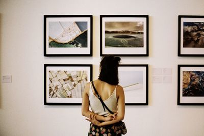 Rear view of woman standing against wall in museum