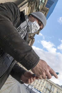 Low angle view of man holding umbrella against sky