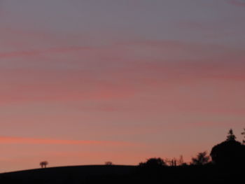 Scenic view of silhouette field against orange sky