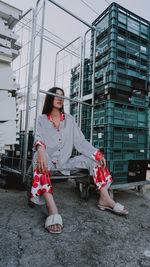 Full length of woman sitting against building in city