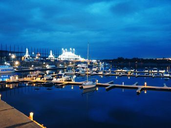 Sailboats moored on harbor against sky at night