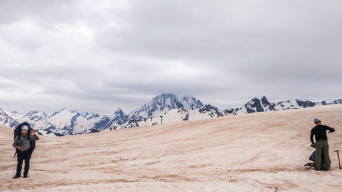 Rear view of people on snowcapped mountain against sky