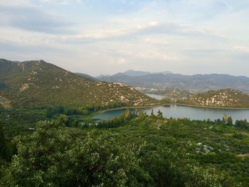 Scenic view of river by mountains against sky