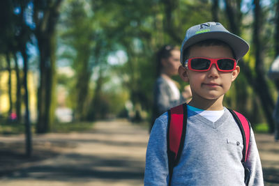 Portrait of boy wearing sunglasses and cap standing in park