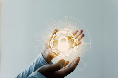 Midsection of person holding light bulb against white background