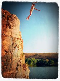 Full length of man jumping on rock against sea