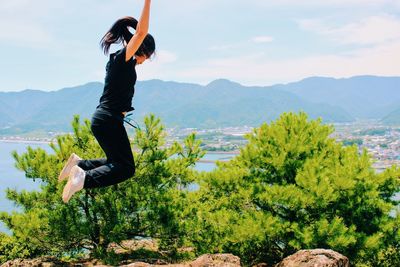 Side view of woman jumping against mountains