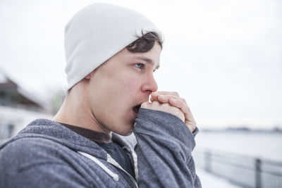 Portrait of young man looking away against sky