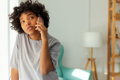 Portrait of young woman using mobile phone while sitting at home