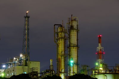 Low angle view of illuminated factory against sky at night