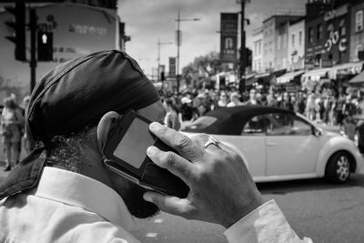 Midsection of man using mobile phone on street in city