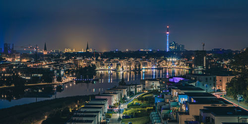 High angle view of illuminated buildings by river against sky