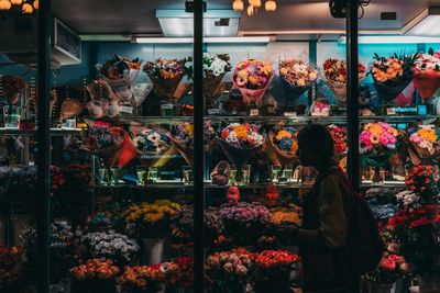 Woman standing by flower shop in city