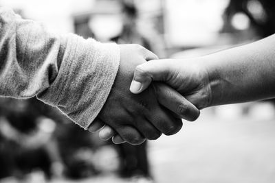 Close-up of friends holding hands outdoors