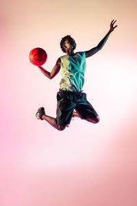 Full length of man jumping against gray background