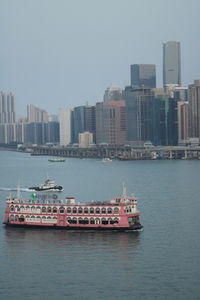 Nautical vessel on sea by buildings against clear sky