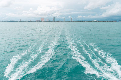 Sea wave from catamaran yacht engine with pattaya beach and sky in the background.
