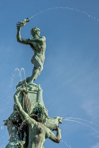 Low angle view of brabo statue at antwerp grote markt square against blue sky