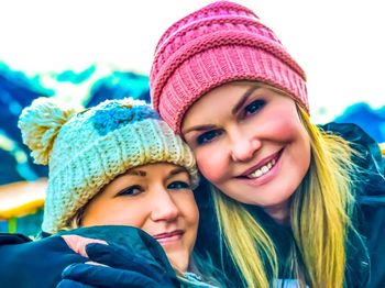 Close-up portrait of smiling sisters wearing knit hats