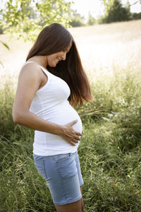 Side view of young woman standing on grassy field