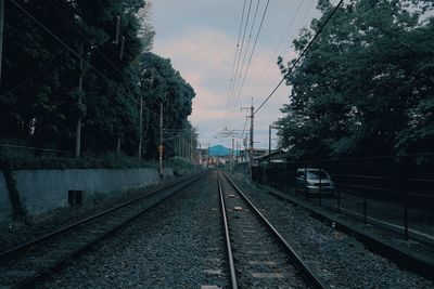 Railroad tracks by trees against sky