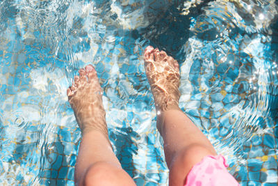 Low section of woman relaxing in swimming pool