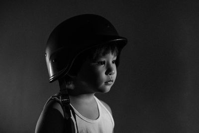 Portrait of boy looking away against black background