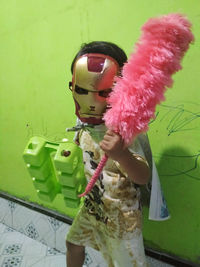 Midsection of woman holding umbrella standing against wall