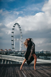 Full length of young woman standing against sky